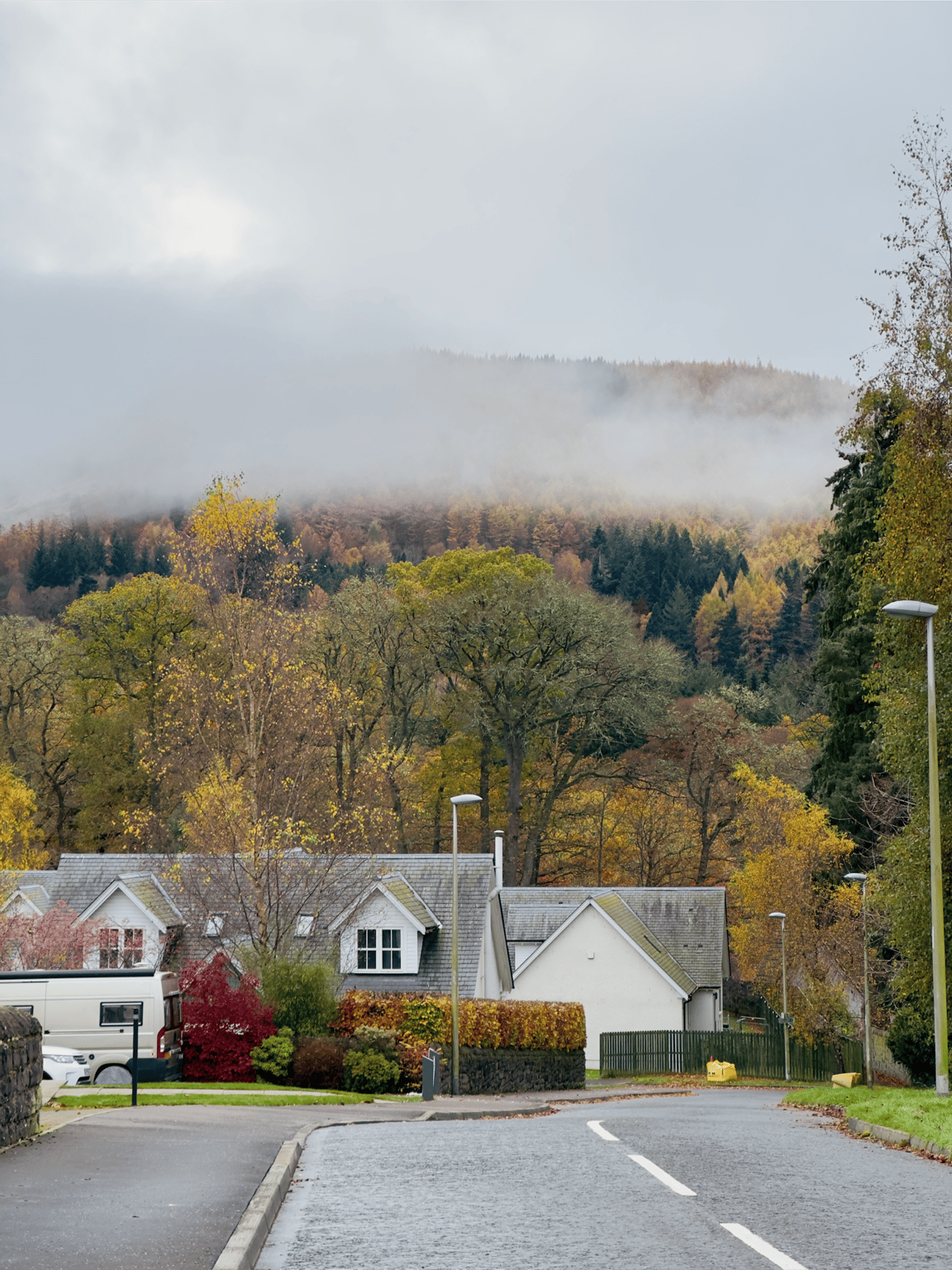 A serene Pitlochry Scotland during November autumn, with mist covering colorful forested hills a